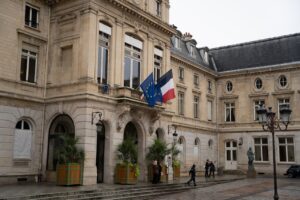 Historic French building with EU and French flags in a serene courtyard setting.