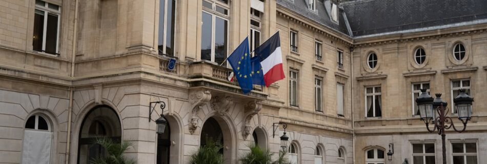 Historic French building with EU and French flags in a serene courtyard setting.